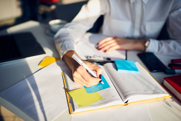 Cropped image of creative female secretary creating planning for executive noting important meeting and events organizing work of busy boss while sitting at working place in coworking office